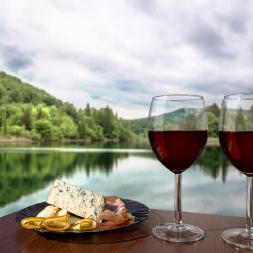 Two,Glasses,Of,Wine,With,Charcuterie,Assortment,On,Calm,Lake